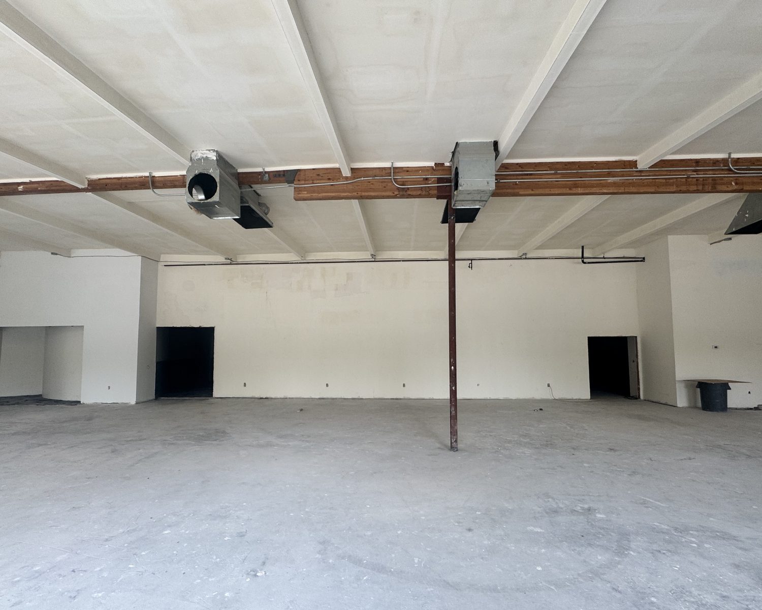 Rear of Suite A-14 with exposed beams, ducting and two doorways to back-of-house